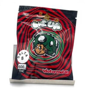 One Up Gummies Watermelon packaging featuring vibrant watermelon-themed graphics and colorful gummy candies, designed for a delicious psilocybin experience, showcasing a fun and flavorful treat
